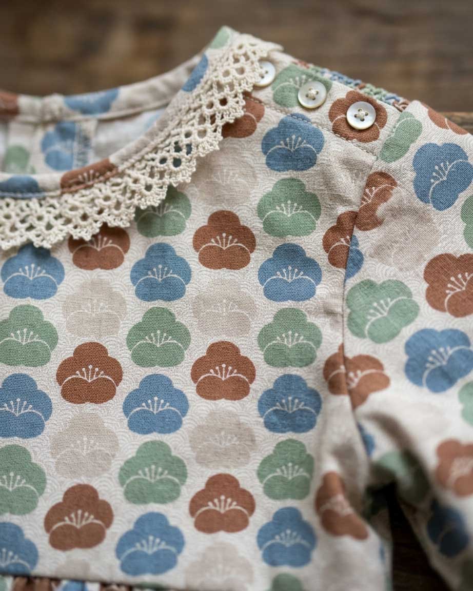 Close-up of a children’s dress featuring the Blossom Wave Dusty Blue pattern in soft blue, sage, clay, and cream by Studio Meggi.