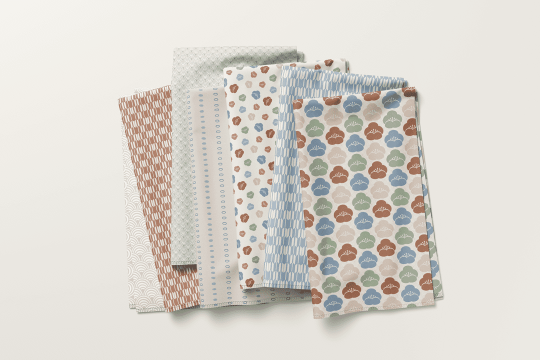 Folded fabric stack from the Seigaiha Bloom collection with florals, waves, dots, and geometric prints by Studio Meggi.